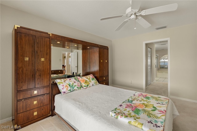 bedroom featuring light colored carpet, ceiling fan, and connected bathroom