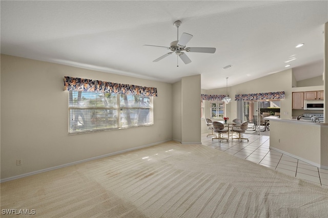 carpeted spare room with ceiling fan with notable chandelier, a wealth of natural light, and lofted ceiling