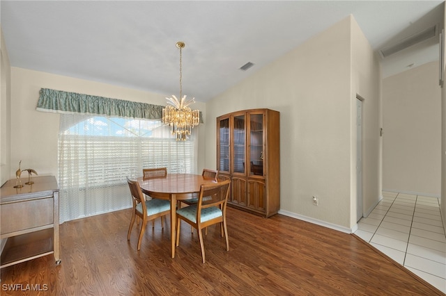 dining area with wood-type flooring and an inviting chandelier