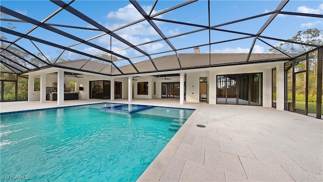 view of swimming pool with a patio, ceiling fan, glass enclosure, and an in ground hot tub