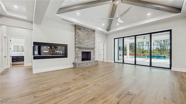 unfurnished living room with a fireplace, light hardwood / wood-style floors, a towering ceiling, and ceiling fan