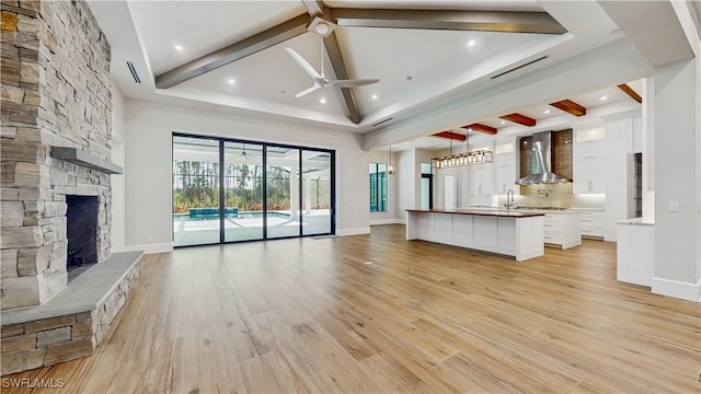 unfurnished living room featuring a fireplace, sink, a high ceiling, light hardwood / wood-style flooring, and ceiling fan