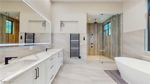 bathroom with plus walk in shower, vanity, a wealth of natural light, and tile walls