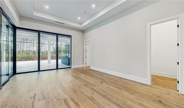 spare room featuring light wood-type flooring, ceiling fan, and a tray ceiling