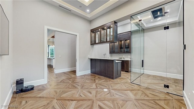 bar with light parquet flooring, dark brown cabinetry, and a towering ceiling