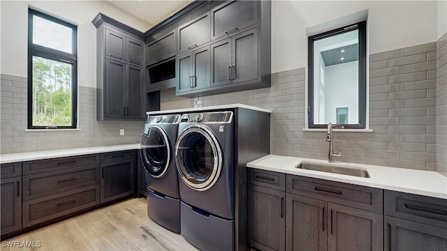 washroom with sink, light hardwood / wood-style flooring, washing machine and dryer, and cabinets