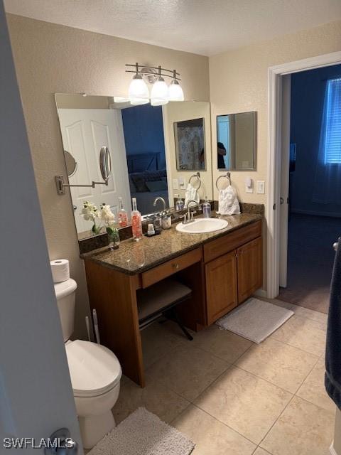 bathroom with vanity, a textured ceiling, tile patterned floors, and toilet