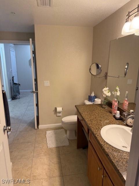 bathroom featuring vanity, a textured ceiling, tile patterned floors, and toilet