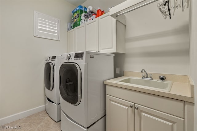 clothes washing area with cabinets, light tile patterned floors, washer and clothes dryer, and sink