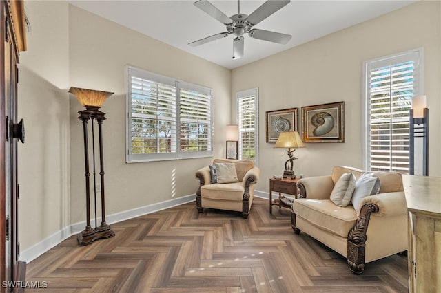 living area with dark parquet flooring, ceiling fan, and a healthy amount of sunlight