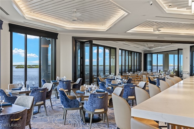 dining room with a raised ceiling, plenty of natural light, wood ceiling, and a water view