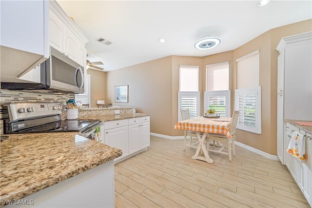 kitchen featuring light stone countertops, appliances with stainless steel finishes, light hardwood / wood-style floors, and white cabinetry