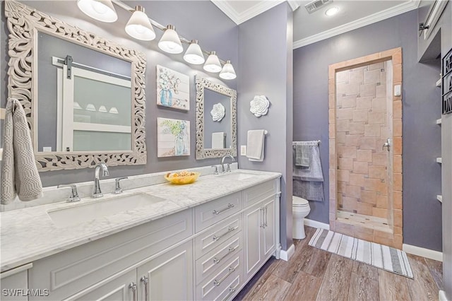 bathroom featuring vanity, ornamental molding, hardwood / wood-style floors, toilet, and tiled shower