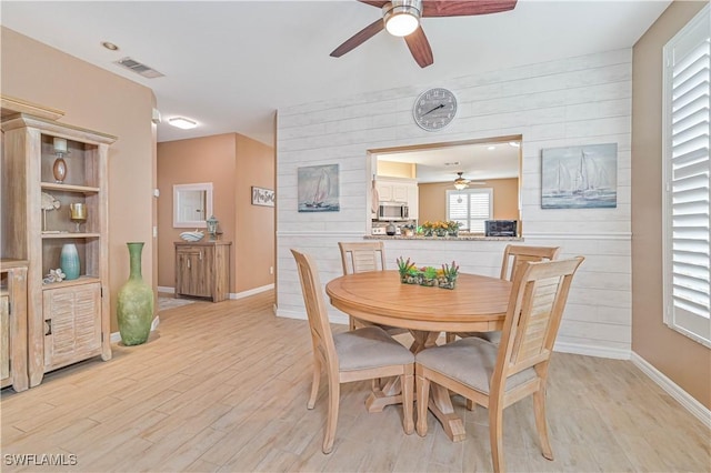 dining space featuring light wood-type flooring and wood walls