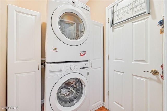 clothes washing area featuring cabinets and stacked washing maching and dryer