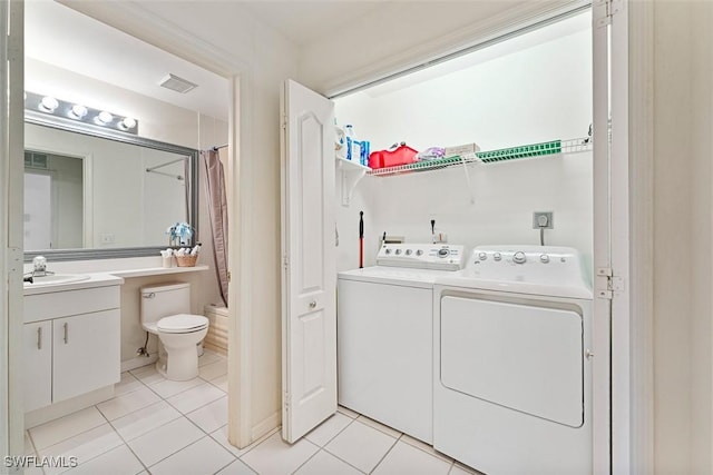 washroom featuring light tile patterned floors, washer and clothes dryer, and sink