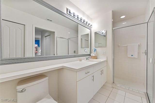 bathroom featuring a shower with shower door, vanity, tile patterned flooring, and toilet