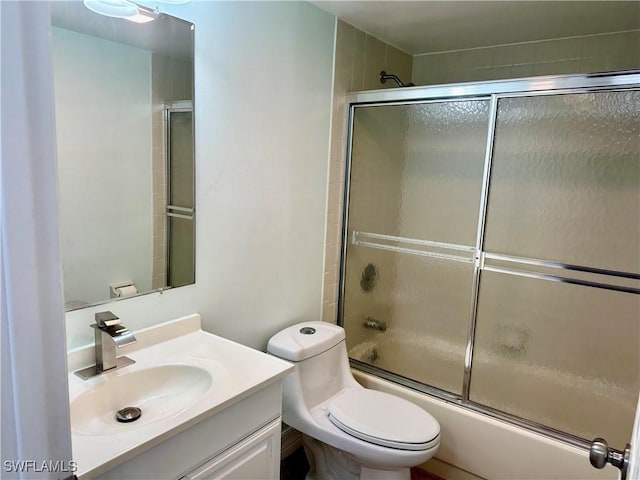 full bathroom with bath / shower combo with glass door, toilet, and vanity