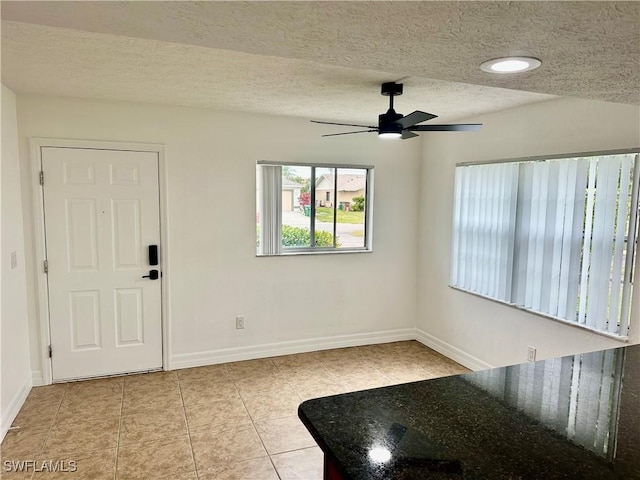 foyer entrance with ceiling fan, a textured ceiling, and light tile patterned floors