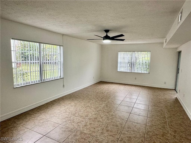 unfurnished room featuring a textured ceiling, ceiling fan, light tile patterned floors, and a healthy amount of sunlight