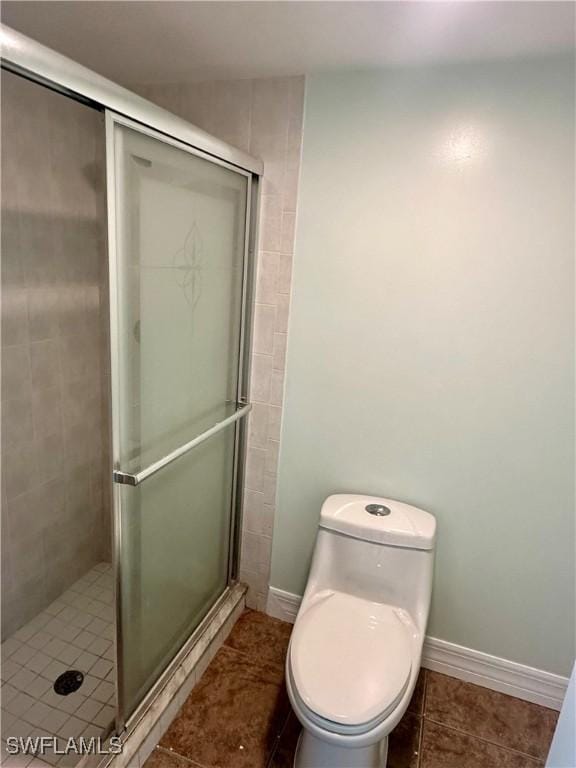 bathroom with toilet, tile patterned floors, and a shower with door