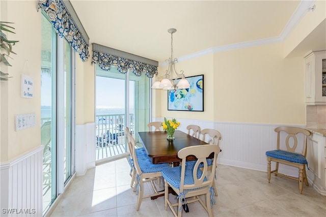 dining space featuring an inviting chandelier, light tile patterned floors, and ornamental molding