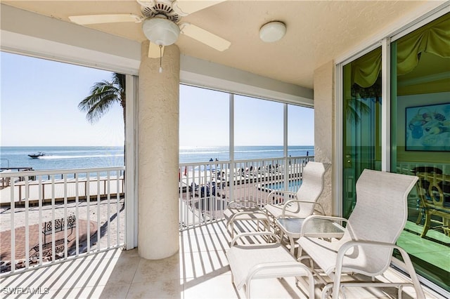 balcony with a water view, ceiling fan, and a view of the beach