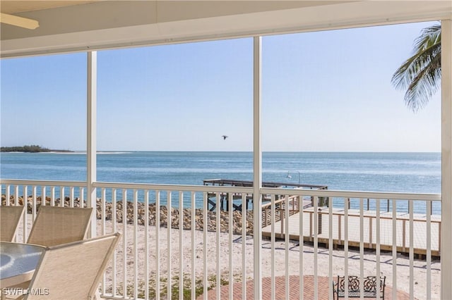 unfurnished sunroom featuring a water view and a view of the beach