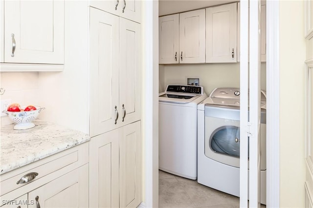 washroom featuring cabinets, light tile patterned flooring, and separate washer and dryer