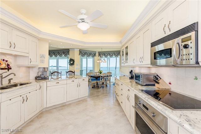 kitchen featuring appliances with stainless steel finishes, white cabinetry, sink, crown molding, and light stone countertops