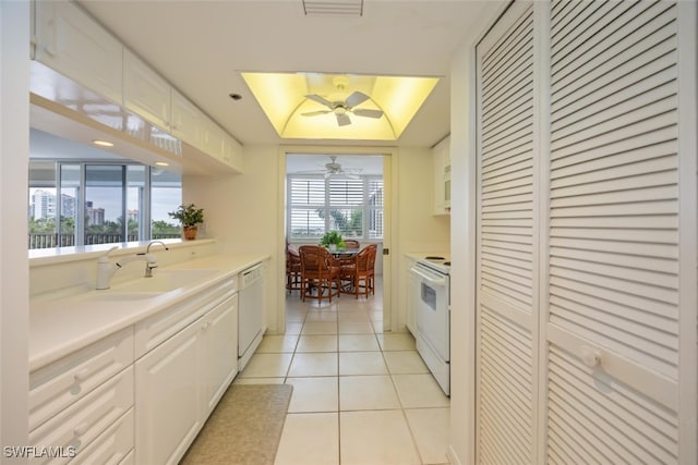 kitchen featuring white appliances, a tray ceiling, white cabinetry, a sink, and light tile patterned flooring