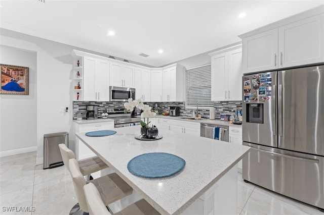 kitchen with appliances with stainless steel finishes, a center island, light stone countertops, white cabinets, and sink