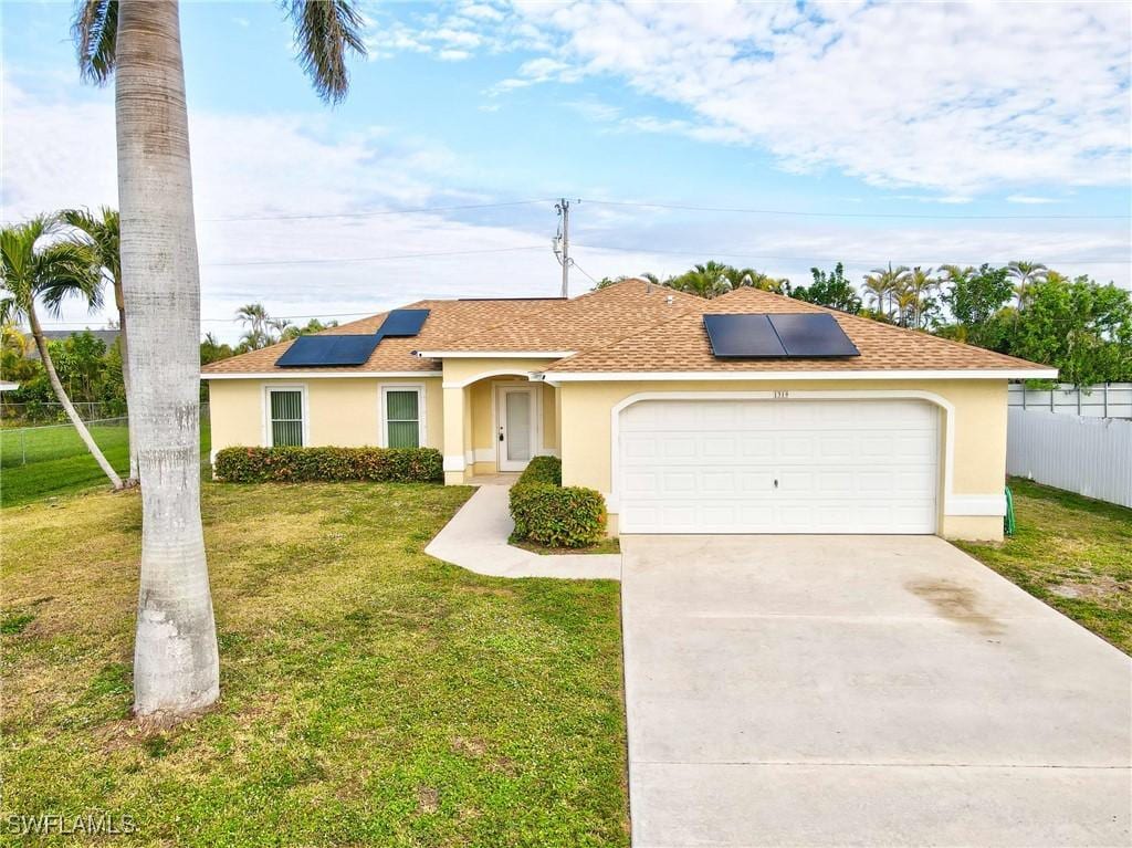 ranch-style house with a front lawn, a garage, and solar panels