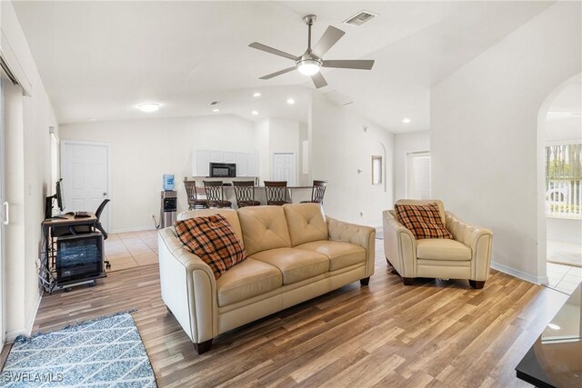 living room featuring ceiling fan, vaulted ceiling, and light hardwood / wood-style floors