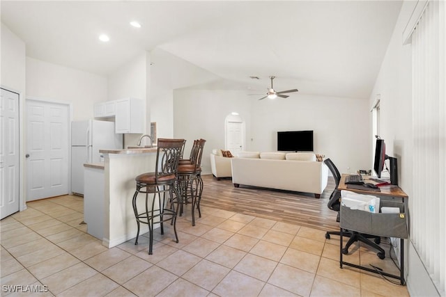 kitchen featuring white cabinetry, kitchen peninsula, a kitchen breakfast bar, light tile patterned flooring, and lofted ceiling