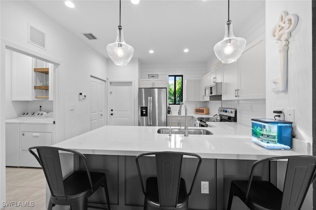 kitchen with white cabinets, separate washer and dryer, pendant lighting, and appliances with stainless steel finishes