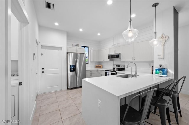 kitchen featuring stainless steel appliances, sink, white cabinetry, kitchen peninsula, and pendant lighting