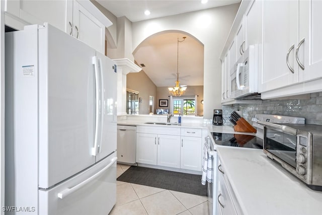 kitchen with light tile patterned flooring, tasteful backsplash, a notable chandelier, white appliances, and white cabinets