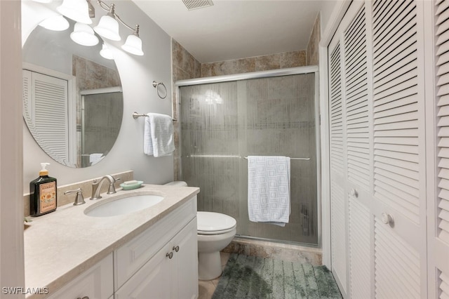 bathroom featuring vanity, a shower with door, and toilet