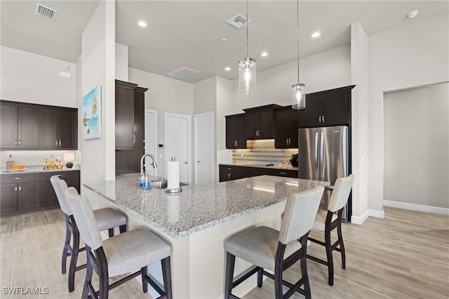 kitchen featuring pendant lighting, kitchen peninsula, sink, a high ceiling, and a kitchen breakfast bar