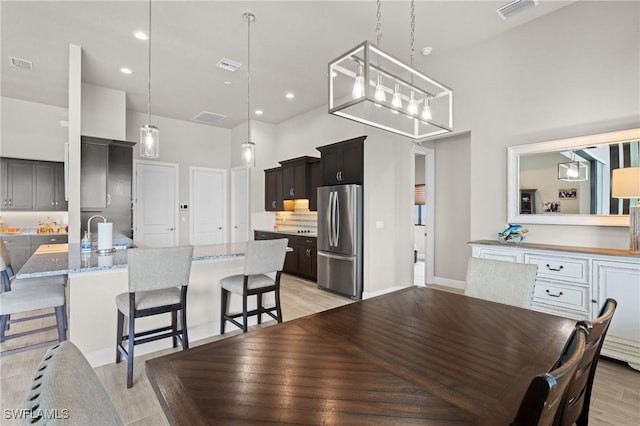 dining room with a high ceiling, sink, and light hardwood / wood-style flooring