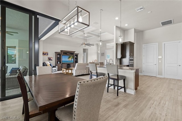 dining area featuring ceiling fan, beamed ceiling, coffered ceiling, and light hardwood / wood-style flooring