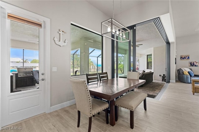 dining area with light hardwood / wood-style floors, a textured ceiling, and ceiling fan with notable chandelier