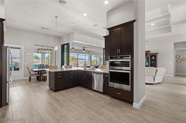 kitchen featuring light wood-type flooring, appliances with stainless steel finishes, sink, and pendant lighting