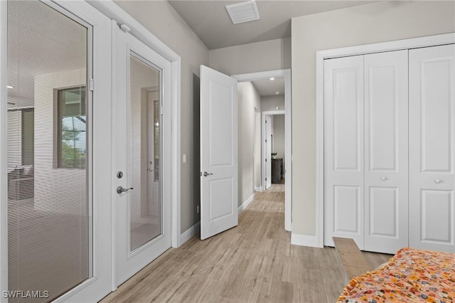 unfurnished bedroom featuring light wood-type flooring, french doors, and a closet