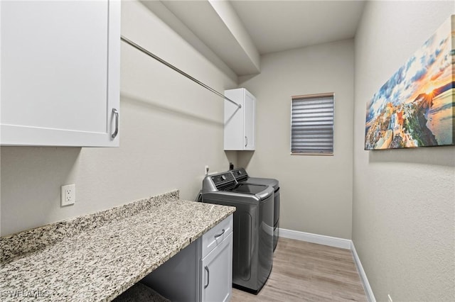 laundry room with cabinets, independent washer and dryer, and light hardwood / wood-style flooring