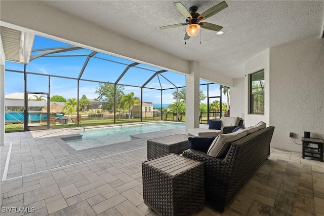 view of pool with ceiling fan, a lanai, outdoor lounge area, and a patio