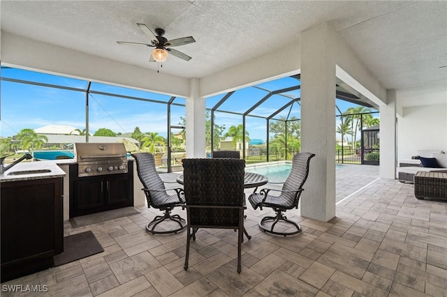 view of patio / terrace featuring grilling area, ceiling fan, sink, and glass enclosure