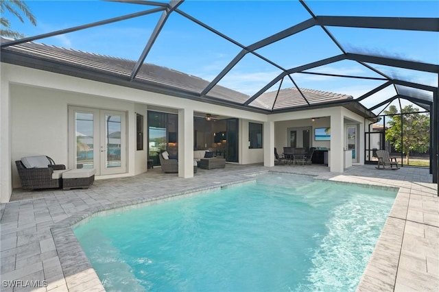 view of pool with glass enclosure, ceiling fan, a patio area, french doors, and outdoor lounge area