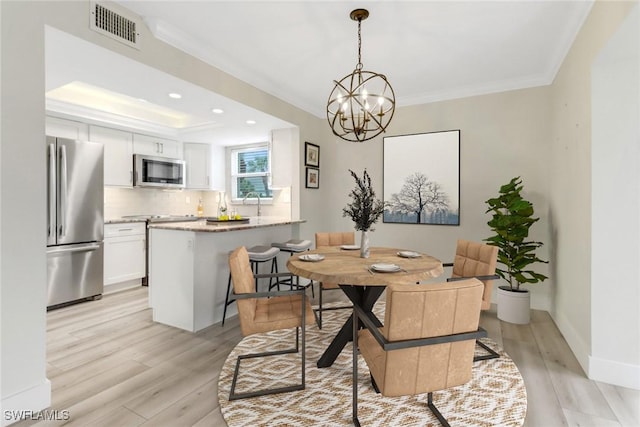 dining area with a chandelier, light wood-type flooring, and ornamental molding